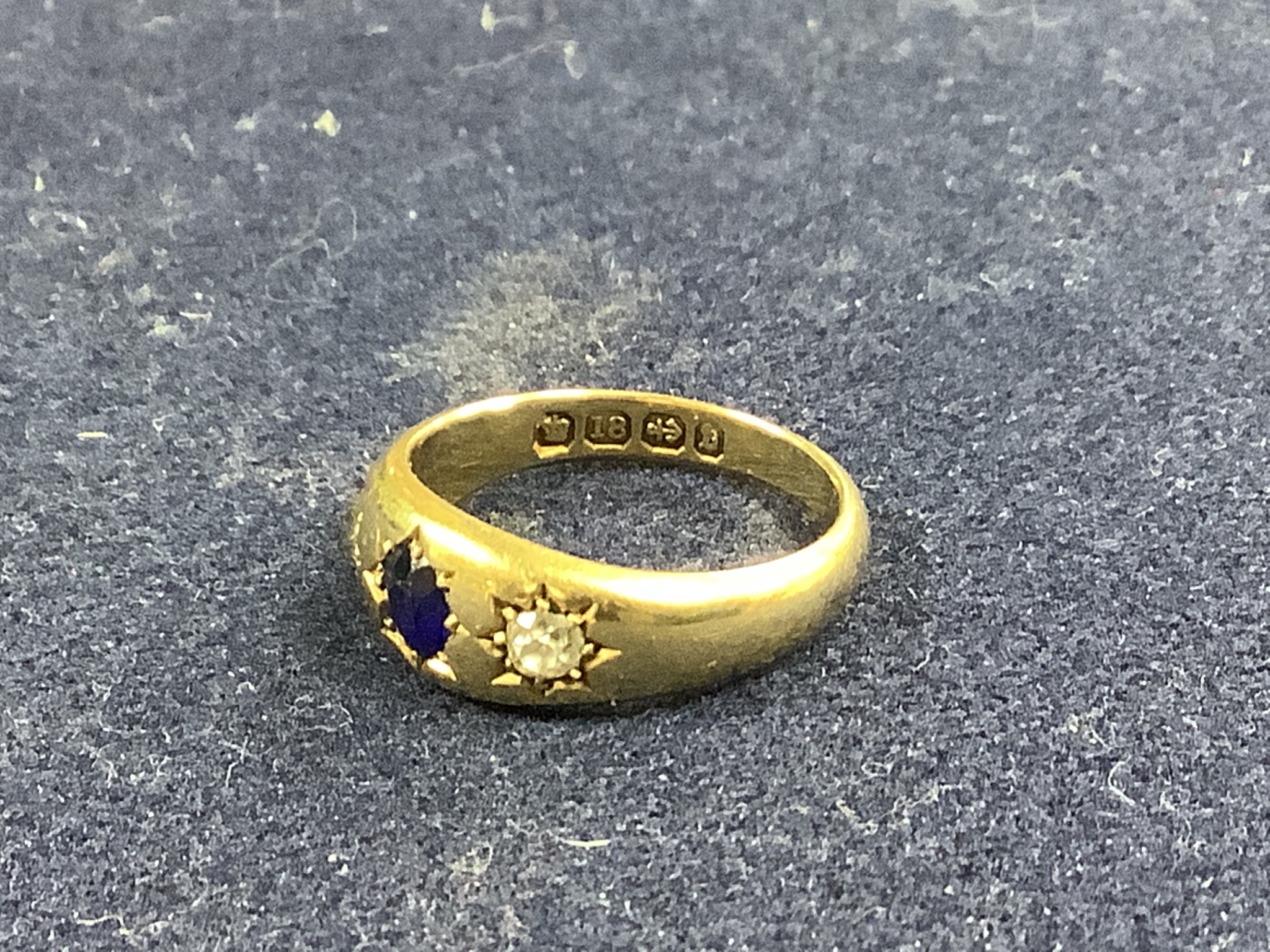 A late Victorian 18ct gold and gypsy set sapphire and diamond three stone ring, size N, gross 5.8 grams.